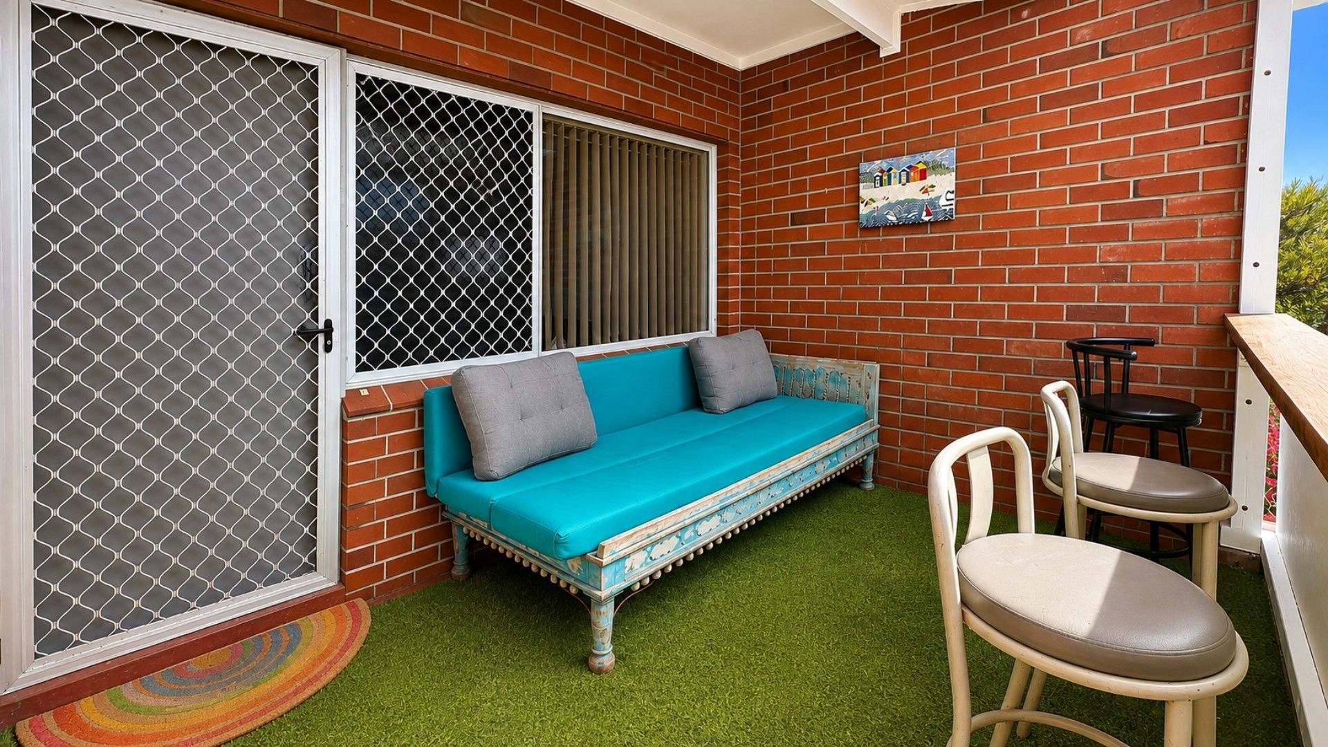 A small outdoor seating area with a blue sofa, two chairs, and a small table.