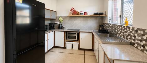A compact kitchen with a black refrigerator, a built-in oven, a coffee maker, and a window with a view.