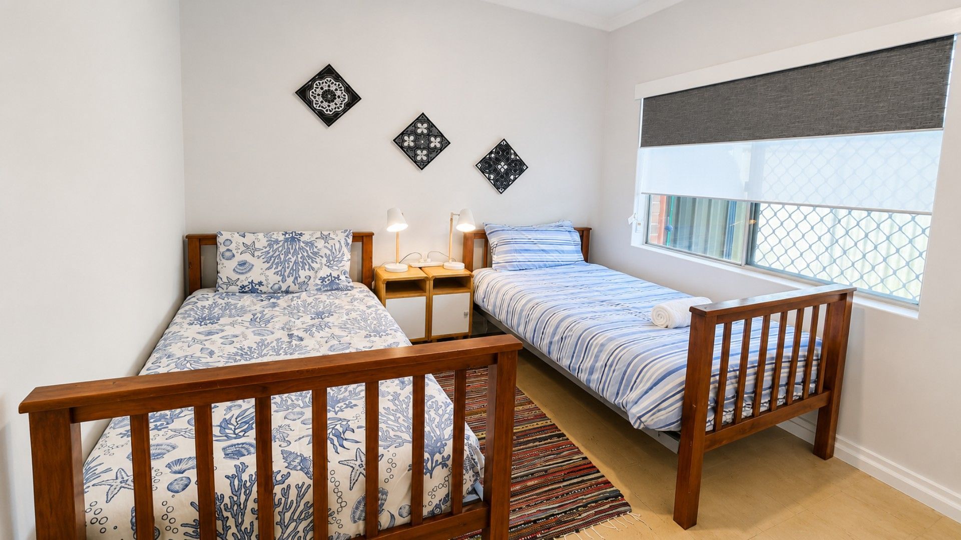 Une chambre avec deux lits simples, une fenêtre donnant sur un beau paysage et des œuvres d’art décoratives au mur.