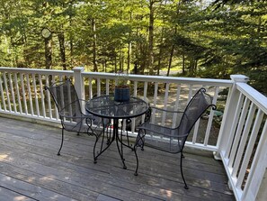 Une terrasse en bois avec une balustrade blanche, une table ronde et deux chaises.