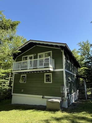 Une maison à deux étages avec un balcon, un porche à l’avant et une cheminée.