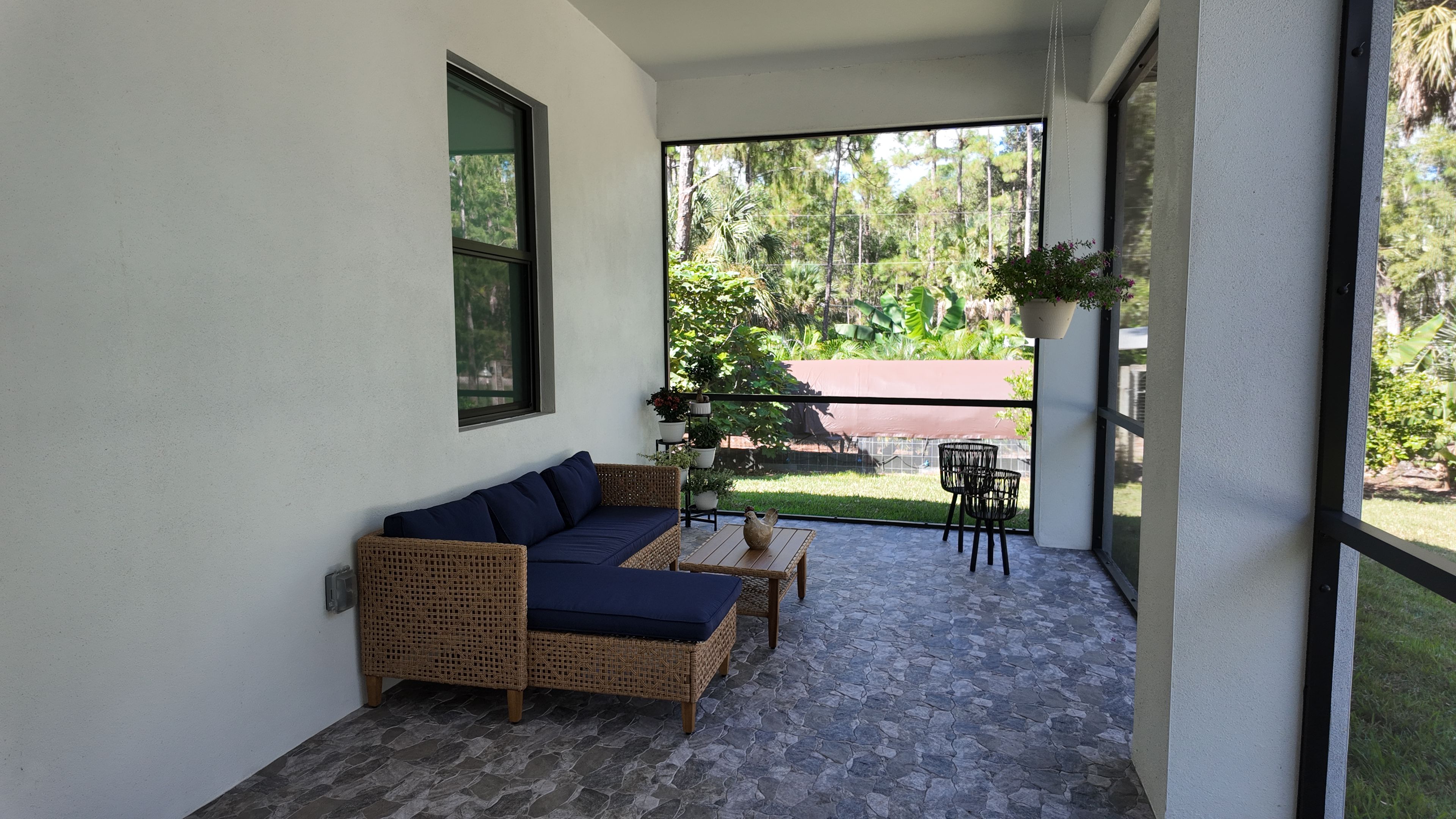A balcony with a wicker sofa, a small table, and chairs.