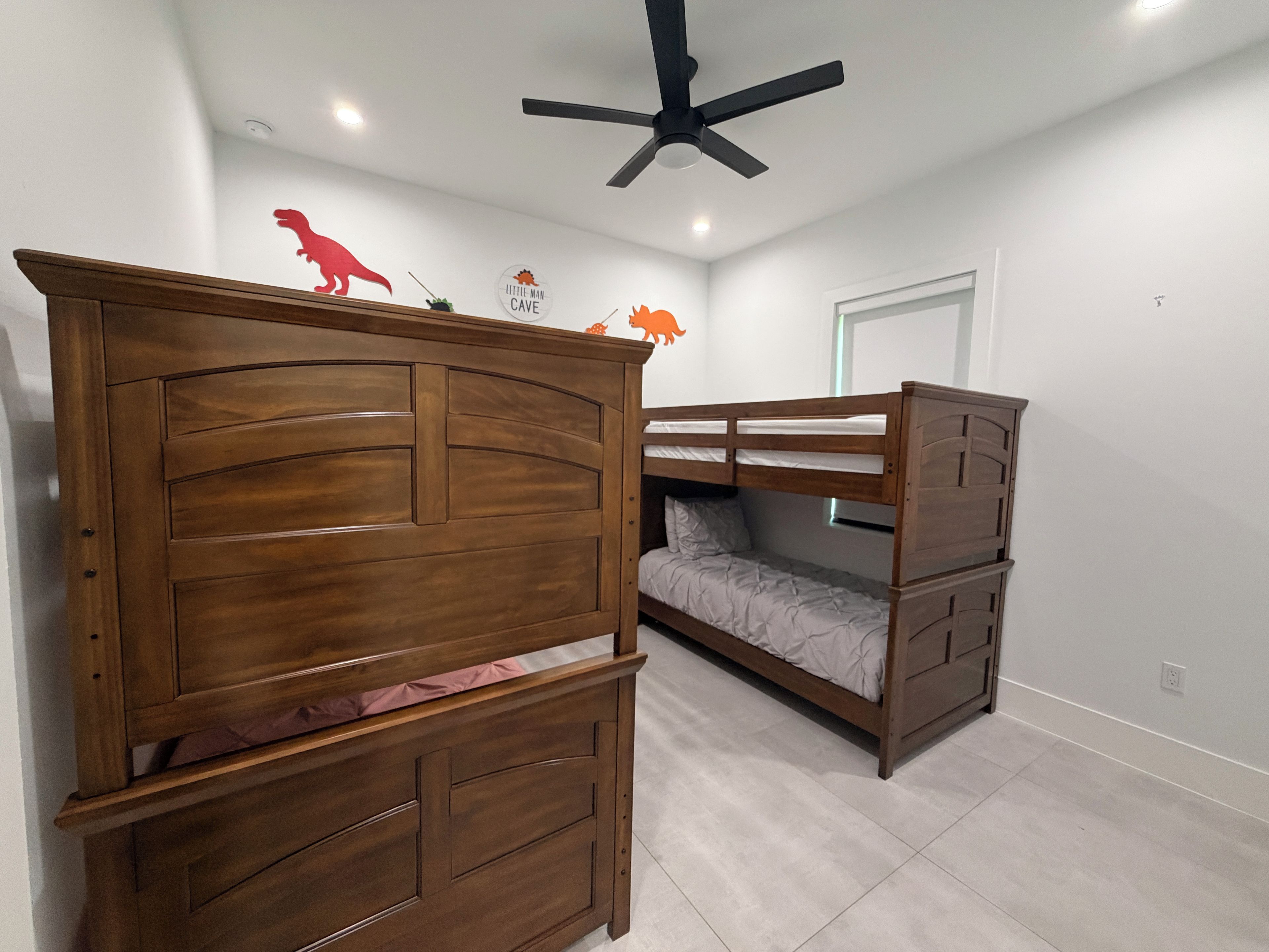 Una habitación con cama de madera, ventilador de techo y literas.