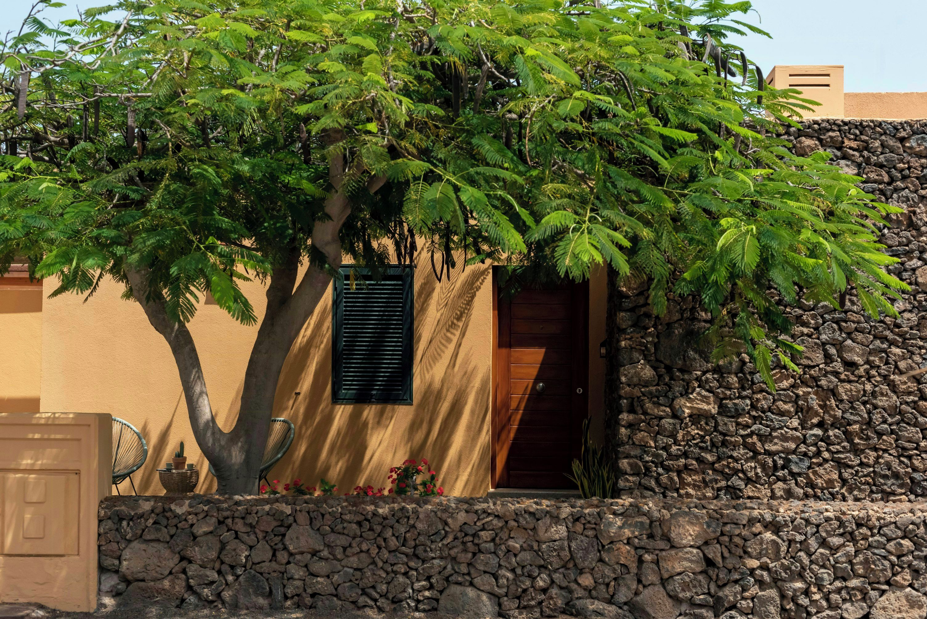 Un bâtiment avec un mur en pierre, une porte en bois et une fenêtre avec des volets.