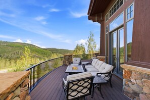 Eine Terrasse mit Gartenmöbeln, einem Feuerkorb und Blick auf eine Berglandschaft.