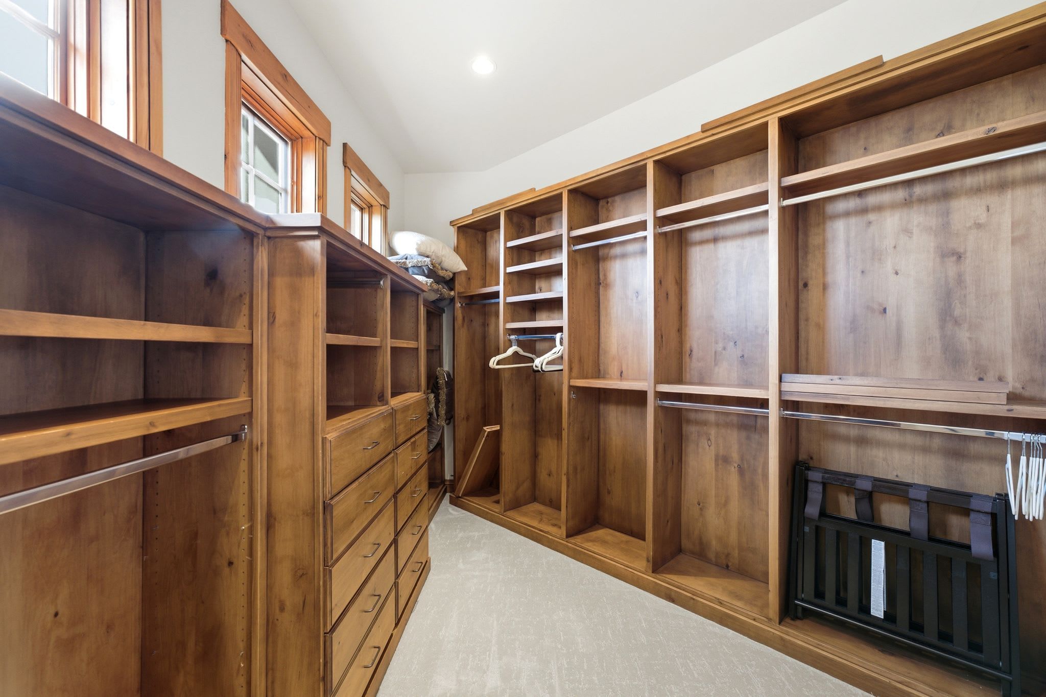 Un dressing avec des étagères en bois, des tiroirs et une tringle pour suspendre les vêtements.