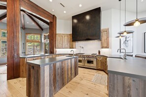A modern kitchen with a central island, wooden cabinetry, and a large stove. - Northside Retreat| Ski-In/Out | Hot Tub (Park City)