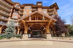 A multi-story hotel with a prominent wooden entrance structure, balconies on each floor, and a stone facade. - Ski-in/Ski-out | Heated Pool, Hot Tubs & Game Room | Shuttle To Main St. (Park City)