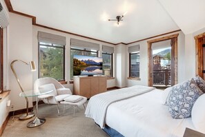 Ein Schlafzimmer mit einem Bett, einem Fernseher, einem Sessel und einem Schreibtisch.