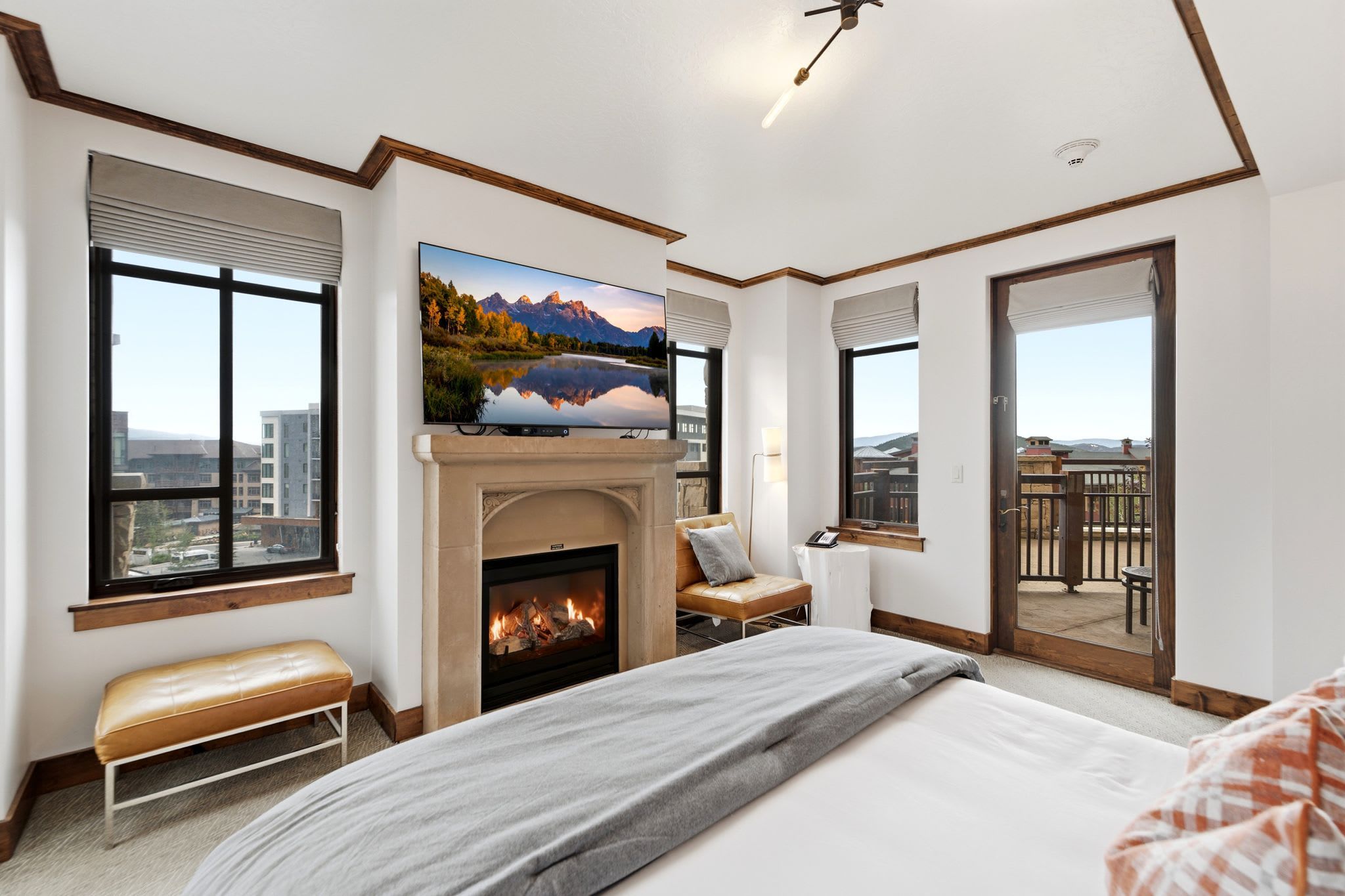 A bedroom with a fireplace, a large window, a sofa, and a balcony.