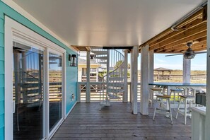 Ein überdachter Außenbereich mit einer Wendeltreppe, einer Holzterrasse und Sitzmöbeln.