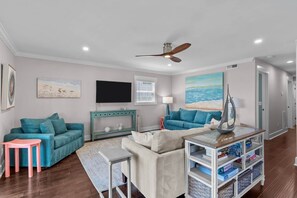 A living room with two sofas, a coffee table, a TV, and a ceiling fan. - Sand By Me - oceanfront house with pool, elevator (Carolina Beach)