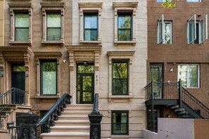 A multi-story building with a central staircase, large windows, and a fire escape. - Modern Queen Room in Central Harlem (New York)