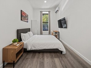 Un dormitorio con cama, mesita de noche y una pequeña mesa con una planta.