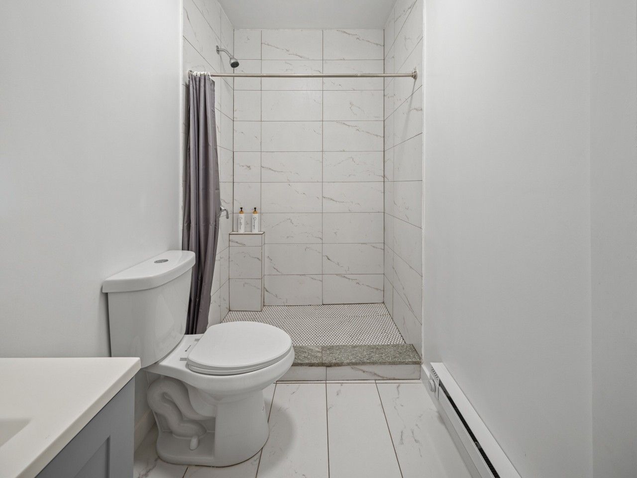 Ein Badezimmer mit Toilette, Dusche und gefliesten Wänden.