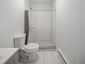Un baño con inodoro, ducha y paredes de azulejos.