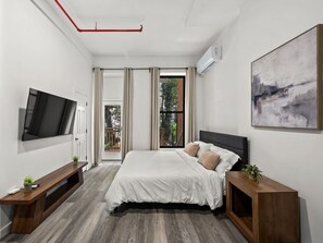 A modern bedroom with a large bed, a flat-screen TV, and a painting on the wall.