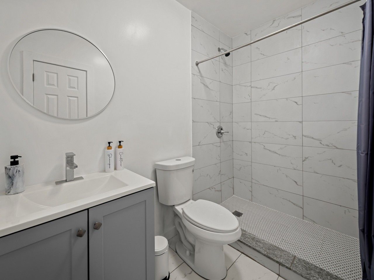 Ein Badezimmer mit Dusche, Toilette, Waschbecken und Spiegel.