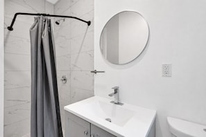 Ein Badezimmer mit Dusche, Waschbecken, Spiegel und Toilette.