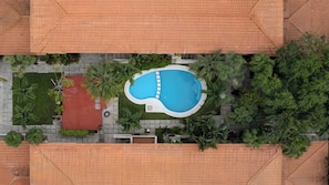 An aerial view of a property with a swimming pool surrounded by greenery and a red area, possibly a patio or deck. - Relaxing apt in privileged Puerto Aventuras area (Puerto Aventuras)