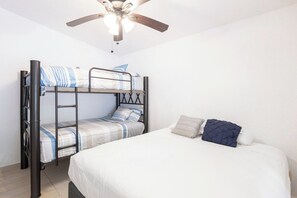 A bunk bed with a ladder, a single bed, and a ceiling fan in a room with white walls. - Relaxing apt in privileged Puerto Aventuras area (Puerto Aventuras)