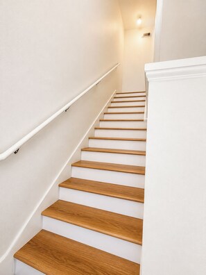Eine Treppe mit hölzernen Stufen und weißen Wänden.