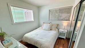 A bedroom with a bed, bedside table, lamp, and a mirror.