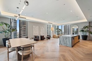 A spacious living area with a dining table, seating, a kitchen island, and large windows offering views of the city. - 501 First Studio Balcony by Palermo Home (Miami)