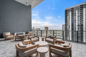 A modern outdoor seating area with multiple chairs and tables, overlooking a cityscape with high-rise buildings. - 501 First Studio Balcony by Palermo Home (Miami)