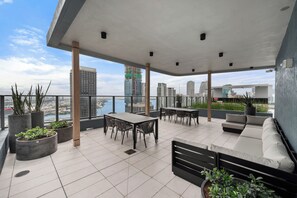 A rooftop terrace with a table and chairs, a sofa, and potted plants. - 501 First Studio Balcony by Palermo Home (Miami)