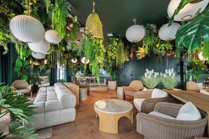 A modern lounge area with a sofa, chairs, a round wooden table, and hanging plants. - 501 First Studio Balcony by Palermo Home (Miami)
