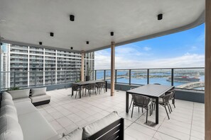 A spacious balcony with a dining table and chairs, a sofa, and a view of a cityscape and water. - 501 First Studio Balcony by Palermo Home (Miami)