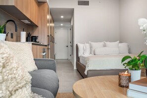 A modern bedroom with a bed, a sofa, a bedside table, and a small table with a candle. - 501 First Studio Balcony by Palermo Home (Miami)