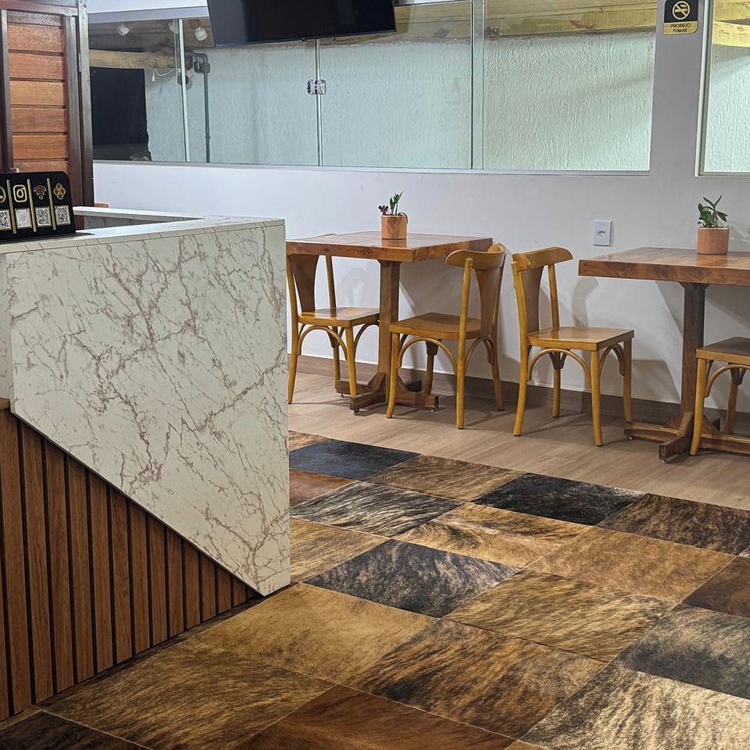 A restaurant interior with a marble counter, wooden chairs, and a patterned floor.