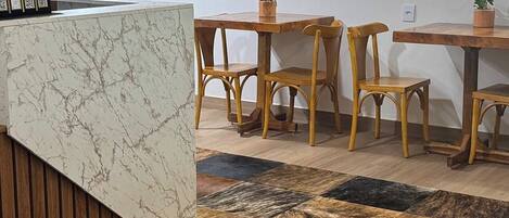 A restaurant interior with a marble counter, wooden chairs, and a patterned floor.