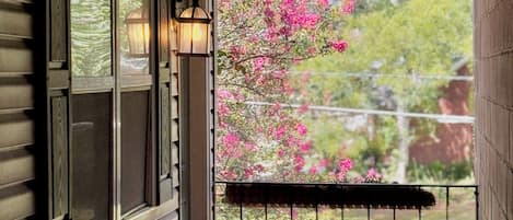 A covered porch with a view of pink flowering trees.