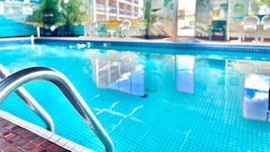 Ein Hallenbad mit klarem, blauem Wasser, einer Metallleiter und einem gefliesten Boden.