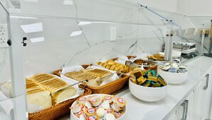Ein reichhaltiges Buffet mit verschiedenen Speisen, darunter Brot, Gebäck und Käse.