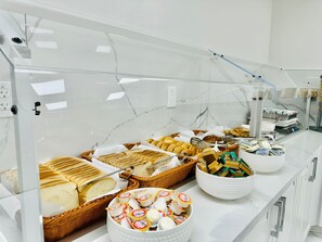 Un buffet proposant une variété d’aliments, notamment du pain, des pâtisseries et du fromage.
