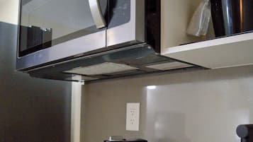 A kitchen with a stainless steel microwave, a coffee maker, and a sink.