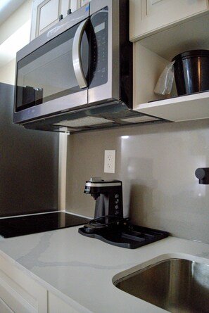 A kitchen with a stainless steel microwave, a coffee maker, and a sink. - Bachelor Unit on Niagara Gorge w private kitchen and free breakfast! (Niagara Falls)