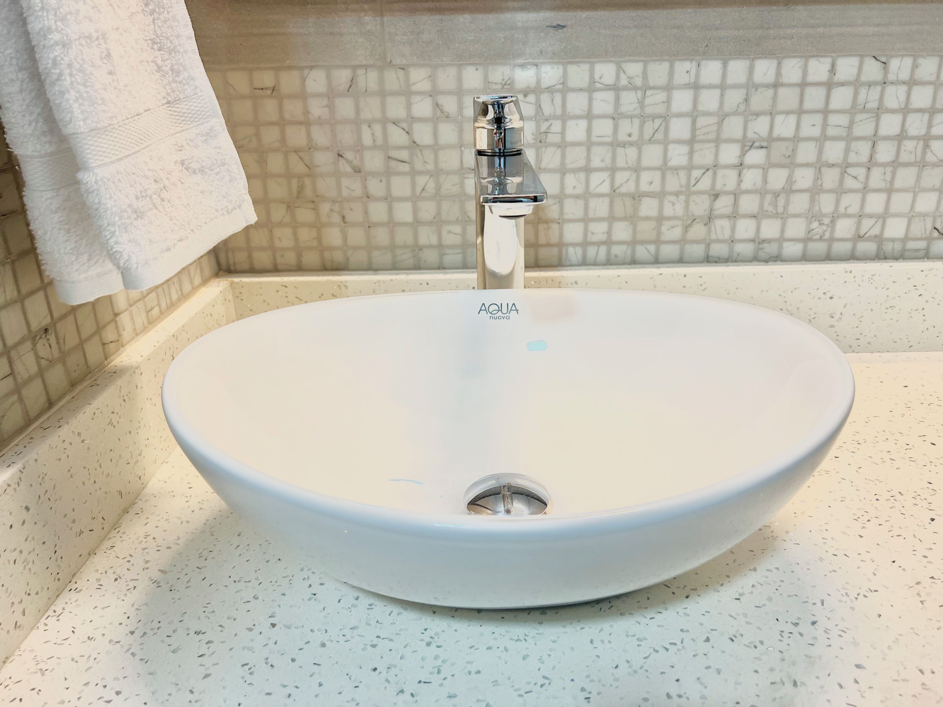 Une salle de bain avec un lavabo blanc, un robinet et un mur recouvert de carreaux.