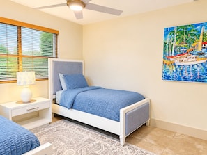 A bedroom with a bed, nightstand, lamp, and a painting on the wall.