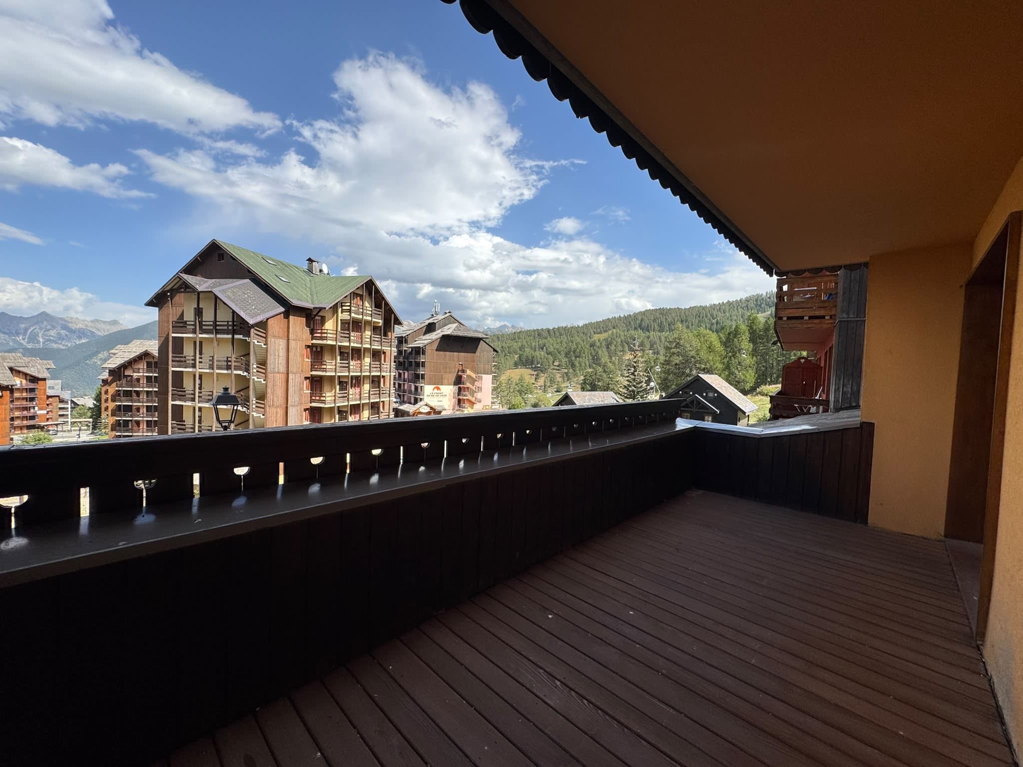 Una terraza de madera con vista a edificios de montaña y cielo despejado.