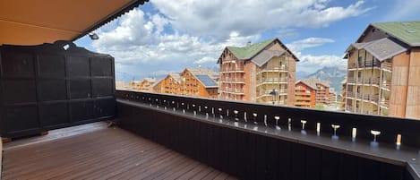 A wooden deck with a view of traditional chalet-style buildings and mountains in the background.