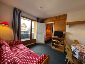Ein gemütliches Zimmer mit einem Bett, einem Fernseher, einem kleinen Tisch und einem Fenster mit Vorhängen.