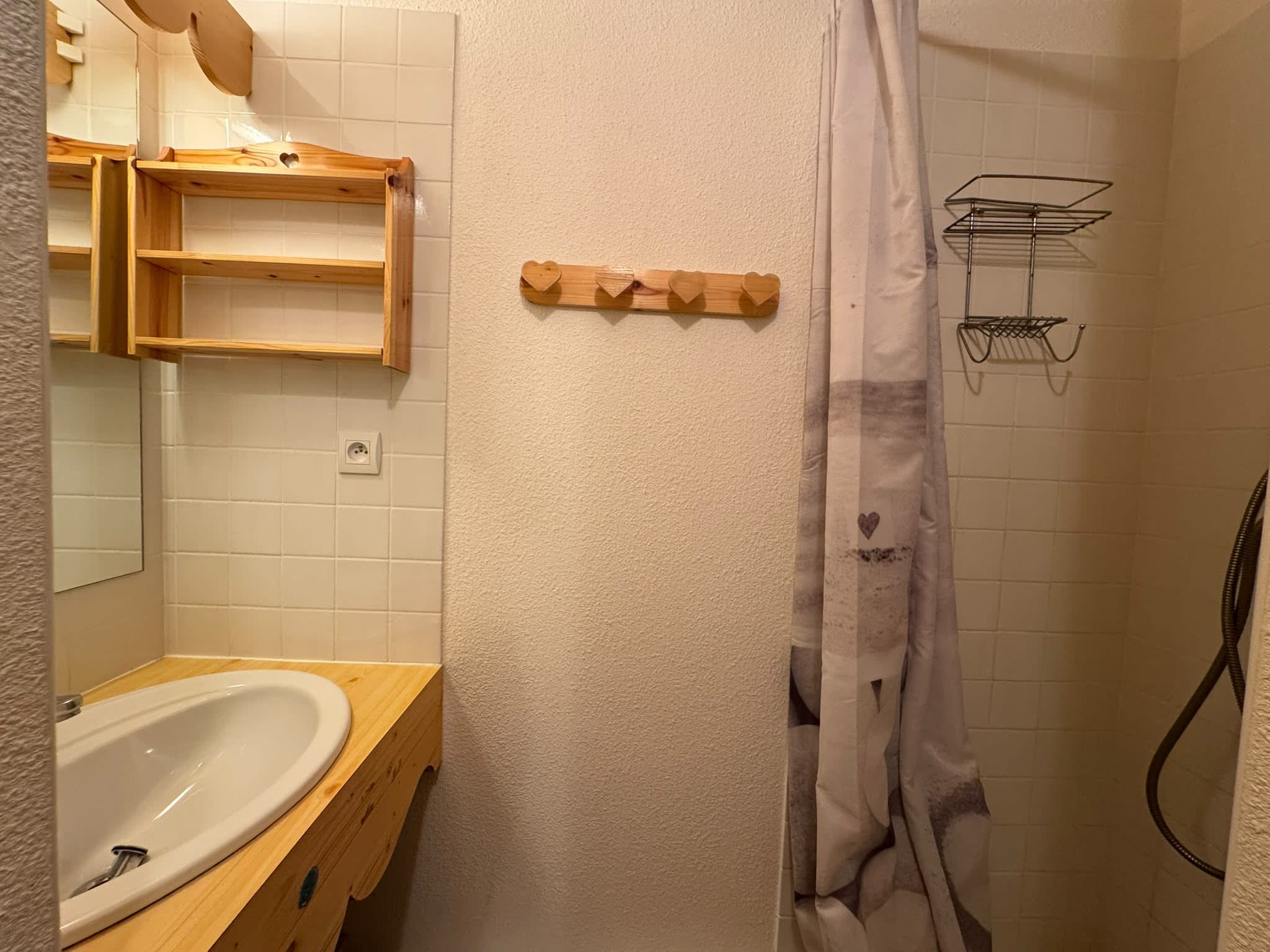 A bathroom with a wooden vanity, a white sink, a towel rack, and a shower curtain.