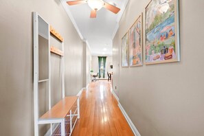 A hallway with a wooden bench, a ceiling fan, and framed artwork on the walls. - Chic Urban Oasis min NYC & MetLife - 1100 sqft (Hoboken)