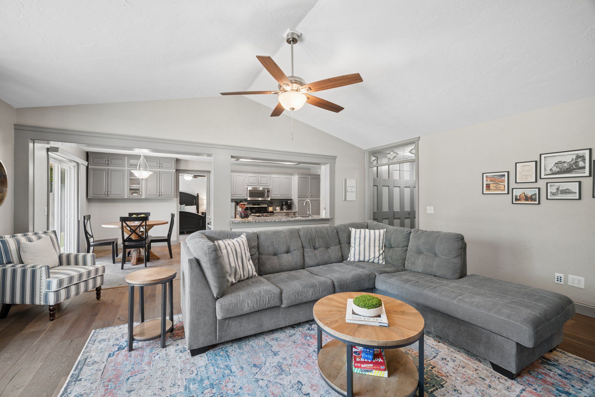 A spacious living room with a grey sectional sofa, a round coffee table, and a ceiling fan.