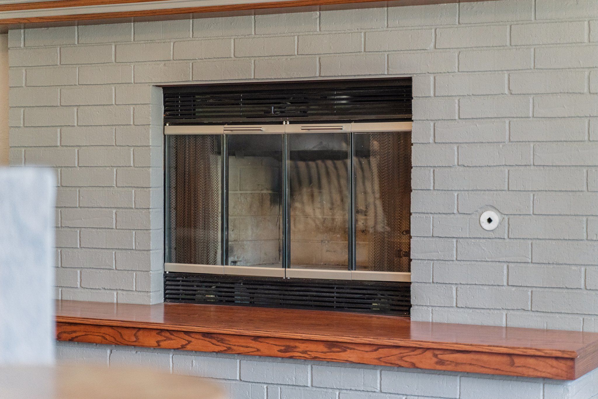 A fireplace with a glass door, set in a brick wall.